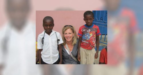 A woman poses with two Haitian boys.