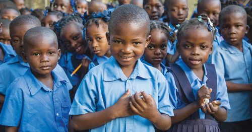 A group of Haitian children wearing blue school uniforms.