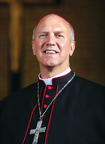 A man with gray hair smiles in his bishop vestments.