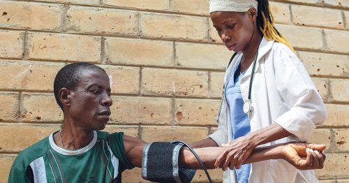 A health worker takes a man’s blood pressure at a Catholic mobile clinic in Malawi.