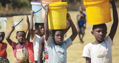 Children carry five gallon water buckets on their head.