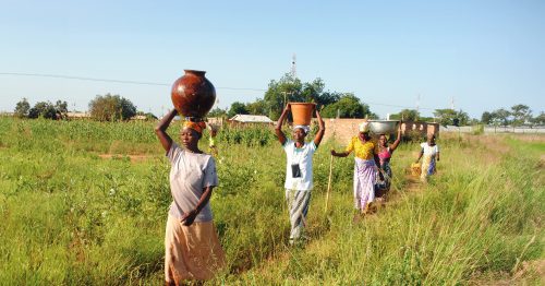 Women in Ghana carry carry water in large basins on their heads.