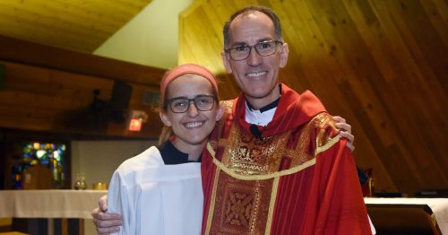 A priest stands with an altar server.