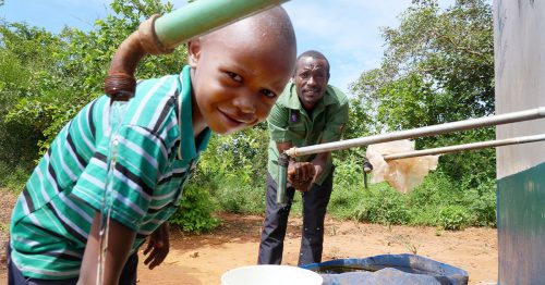 A young boy and his father fill containers with clean water from their water system.