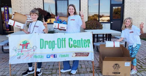 Children hold up a sign at a Box of Joy Drop-Off Center in Frankfort, Illinois.
