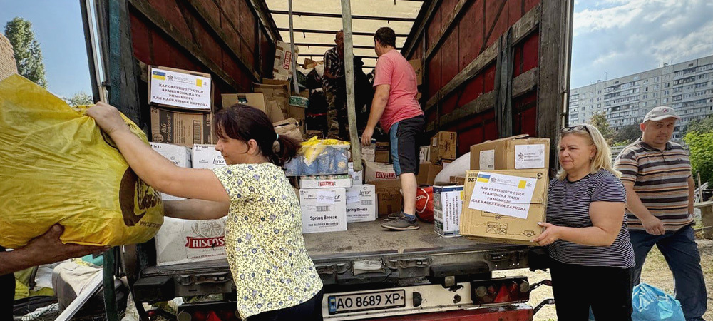 People unload boxes of supplies from the back of a truck.