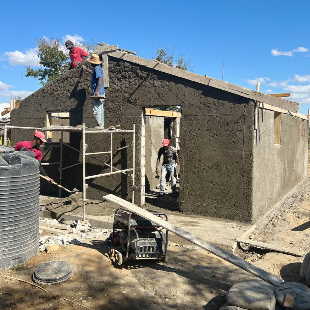 A group of workers smooths the walls of a new house under construction.