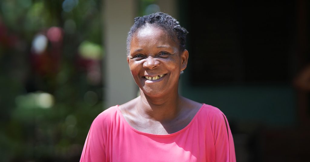 A woman in a pink blouse smiles at the camera.