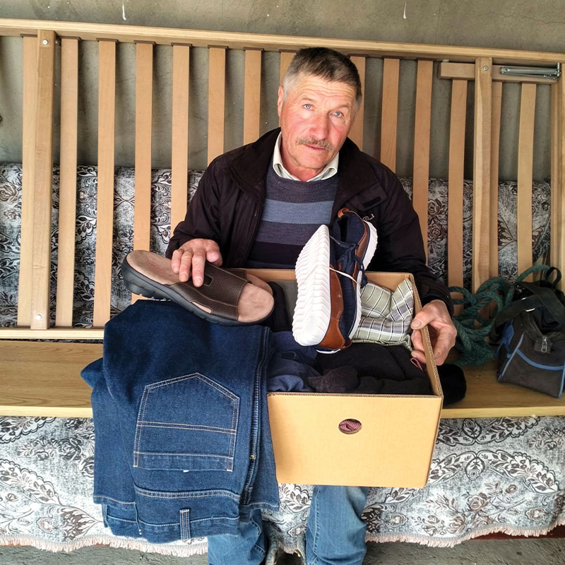 A man holds a box with shoes, pants and other personal care items.