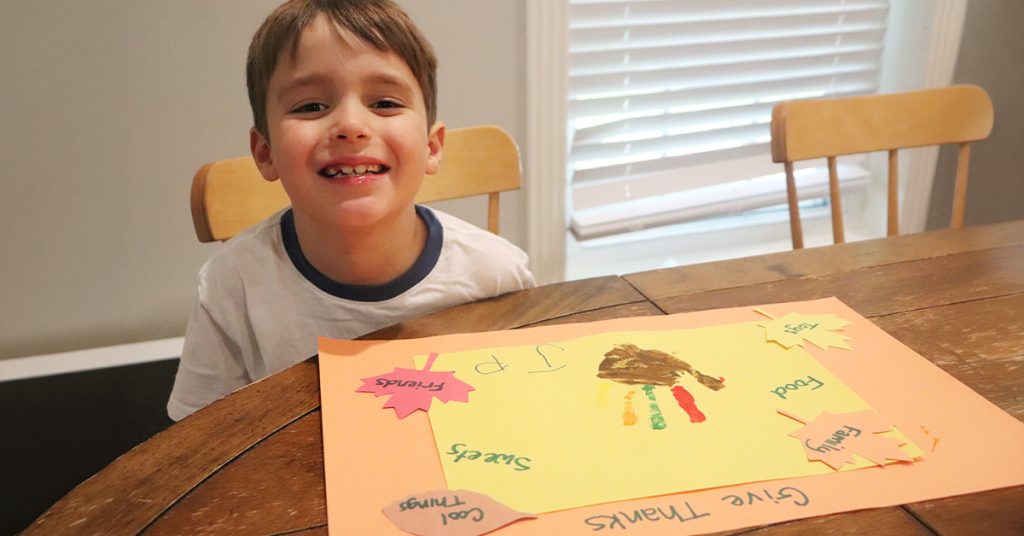 A little boy smiles as he sits at his Thanksgiving placemat.