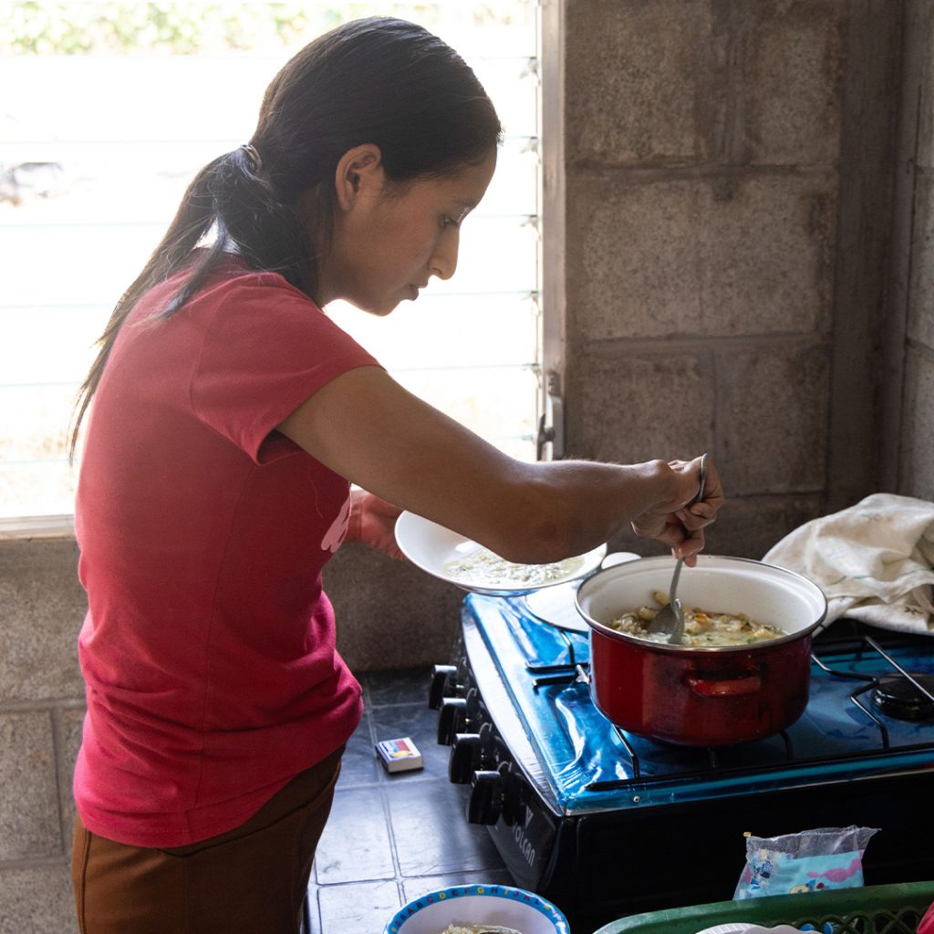 Una mujer cocina para su familia junto a la estufa.