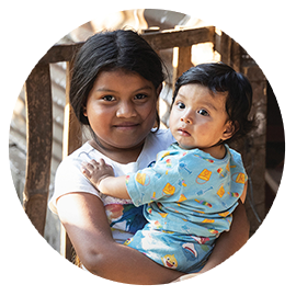 A girl from Guatemala is pictured holding her younger sister in her arms