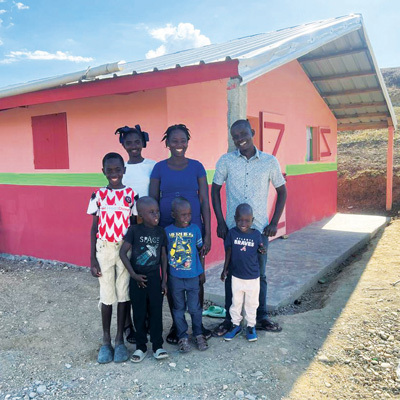 A Haitian family stands outside their safe new home.